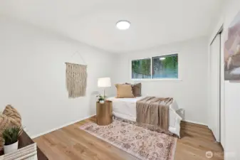 A cozy third bedroom with LVP flooring, a sliding closet door, and a window with green backyard views, offering a calm and versatile space.