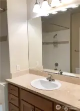 Primary bathroom features quartz counters and tile tub/shower surround.