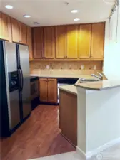 Kitchen features plenty of cupboard and counter space. Pendant lighting over the breakfast bar. Pantry is to the left of the refrigerator.