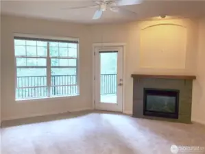 Living room features ceiling fan, gas fireplace, plenty of light, and a door to the generous balcony.