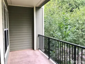 Another view of the balcony. The view looks out over a forested area that is peaceful and serene.