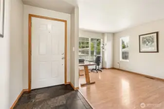 Meet the entryway that moonlights as a mood board with dark slate, crisp white door, warm laminate floors, and just enough windows to make your houseplants swoon.