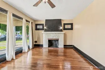 Living room with statement fireplace and HUGE front window that shines loads of natural light on hardwood floors