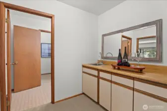 Through the double door opening, this main floor Primary BR suite space provides a wet bar. Full bathroom beyond.