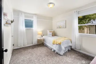 A cheerful secondary bedroom with dual windows that bring in sunshine and views of the yard.