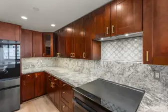 Elegant cooking wall with rich wood cabinets, patterned tile backsplash detail, and expansive workspace for everyday cooking or entertaining.