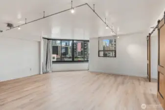 Spacious urban condo living area with large windows with surrounding city views, and an open layout designed for flexible living and entertaining.