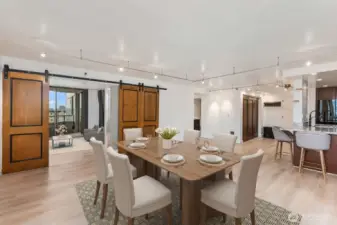 Virtually staged Seattle condo dining area highlighting the open concept layout with sliding barn doors and natural flow between the kitchen, dining, and living spaces.