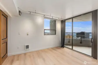 Seattle condo living area with sliding glass doors leading to a private balcony and water views beyond the surrounding cityscape.