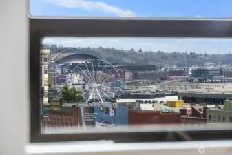 Seattle waterfront skyline view capturing the Seattle Great Wheel, stadium arches, working waterfront, and surrounding downtown buildings.