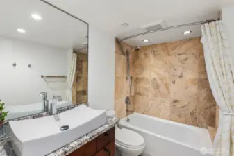 Seattle condo bathroom with single sink vanity, large mirror, and tub shower featuring full wall tile surround.