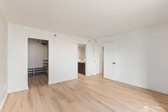 Spacious Seattle condo primary bedroom with wide plank flooring, walk-in closet, and direct access to an attached bathroom.