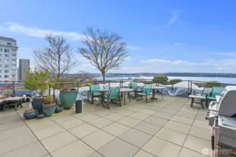 Seattle condo rooftop deck featuring outdoor grilling station, seating areas, and expansive Puget Sound views ideal for relaxing or entertaining.