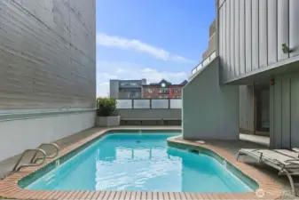 Seattle condo community outdoor pool located in a partially enclosed courtyard setting with lounge seating and surrounding building views.