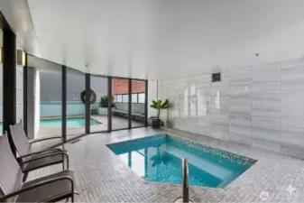 Seattle condo community spa area with indoor hot tub, tiled surround, seating area, and large windows bringing natural light into the space.
