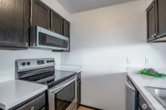 Glass cooktop with a microwave above. Appliances still have the protective film covering them.