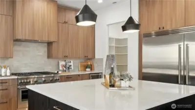 An expansive walk-in pantry provides remarkable convenience, while the high-performance range hood ensures exceptional ventilation for a pristine culinary environment.