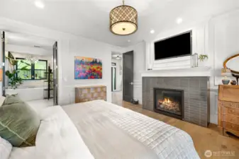 The cozy gas fireplace, 9' ceilings and custom tile and millwork accentuate the primary suite.