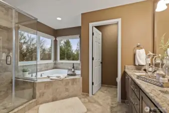 The beautifully redesigned five-piece bathroom contains a soaking tub, separate glass-enclosed shower, dual vanities, and elegant finishes throughout.