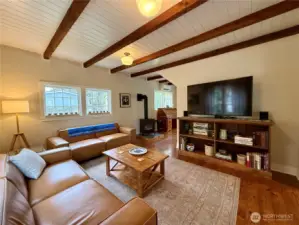 Spacious living room with beamed ceilings and lots of natural light from the picture windows.