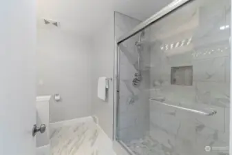 This roomy custom tiled shower with high-end fixtures anchors the main floor bath.