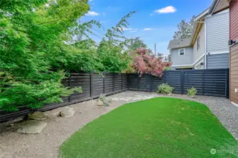 Fully fenced yard with great patio space, easy maintenance synthetic turf grass, garden space, and storage shed.