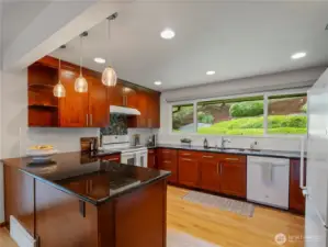Hardwood flooring, granite slab countertops, and cherry cabinets with crown molding.