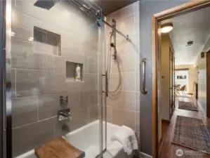 Remodeled shower with tile surround, and original tub.