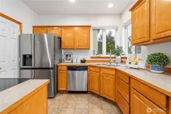 The kitchen is lined with warm oak cabinetry with crown molding and gleaming stainless appliances.