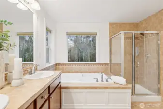 Primary bathroom with double vanity, large soaking tub, shower, and linen closet.