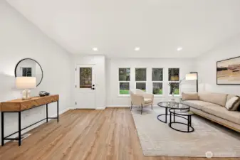 The entry opens to a spacious living room with LVP flooring, recessed lighting, and large windows that fill the space with natural light.