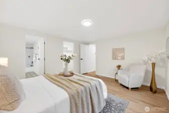 The primary suite features direct access to a private en suite bath and walk-in closet, with LVP flooring and a warm, neutral palette.