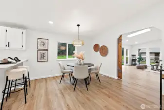 Bright dining space with a rattan pendant light, views to the backyard, and an open doorway leading to an additional bonus living room.