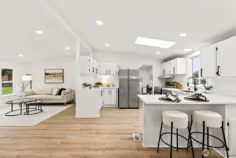 Open-concept kitchen and living room view showcasing the skylight, LVP flooring, peninsula seating, and seamless flow between spaces.
