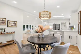 Dining area showcases the rattan pendant, open sightlines to the kitchen and main living room, with recessed lighting and LVP flooring throughout.