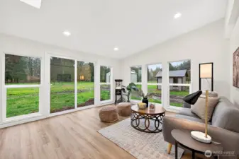 Sun-drenched bonus space with sliding glass door access to the backyard, multiple windows with green views, recessed lighting, and LVP flooring.