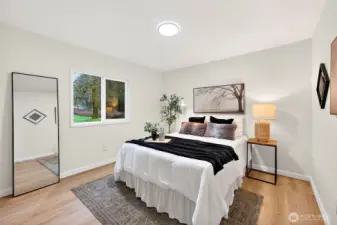 Well-sized bedroom with LVP flooring, a bright window with yard views, and a neutral palette — ideal as a guest room or secondary bedroom.