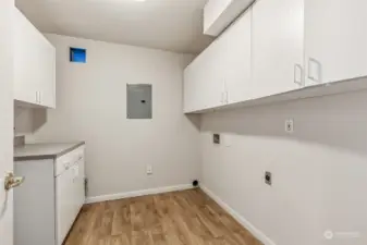 Laundry room with lots of cabinet space, vinyl planked floors & folding table.