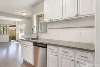 Beautifully updated kitchen showcasing quartz countertops, stainless steel appliances, white cabinetry, and a large window above the sink for plenty of natural light.