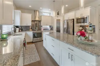 Granite counters and large island are complimented with contrasting full-height subway tile backsplash.