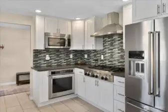 Fully remodeled kitchen, designed with quartz counters, soft-close white shaker cabinets, an apron-front stainless sink, and high-end KitchenAid appliances.