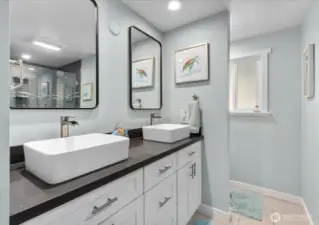 Main bath with a frameless glass shower, quartz counters, double sinks, and new mirrors.