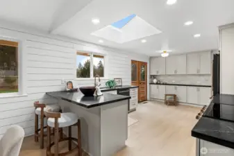 This freshly updated kitchen, with custom cabinetry and high-end finishes, illuminated by an expansive overhead skylight, is re-designed for kitchen excellence.