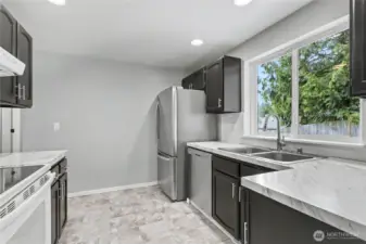 View of your kitchen from the dining room, love the large window over the sink and even more recessed lighting! This is not your typical boring nor claustrophobic alley kitchen, to your left there is an entry to your hallway.