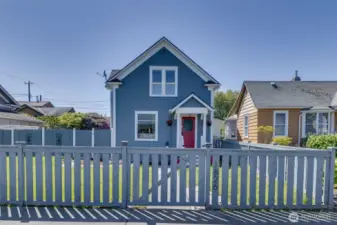 View of the home from the sidewalk, showing newer front fencing.