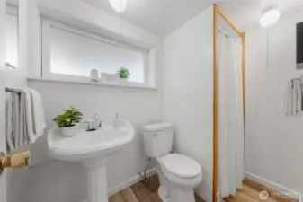 The lower-level bathroom includes a pedestal sink, walk-in shower, and frosted window for added privacy and natural light. Durable vinyl flooring and simple finishes make this space both functional and easy to maintain.
