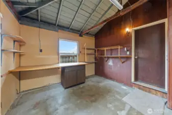 The additional section of the garage offers a dedicated workspace with built-in shelving and a long workbench, ideal for DIY projects or tool storage. A window and utility lighting provide visibility and function for year-round use.