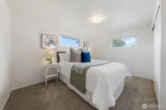 Bedroom One, features two horizontal windows that bring in natural light while maintaining privacy. Soft carpet and neutral walls offer a relaxing and versatile space.