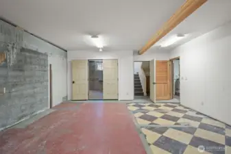 Lower level room shows view toward garage & workshop, stairs up to kitchen and to the right, laundry & unfinished bathroom.