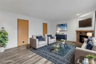Family room with gas fireplace, adjacent half bath, and sliding door to extensive patio; virtually staged.